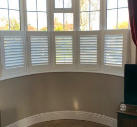 Faux wood shutters in silk white, cafe style, installed to this bay window in Hinckley, Leicestershire : Click Here To View Larger Image